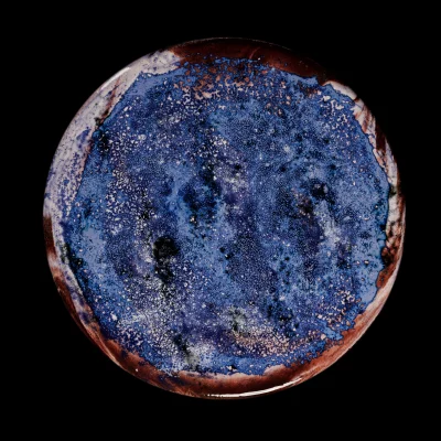 Plateau de table en céramique émaillée aux nuances bleu profond et brun-rougeâtre, évoquant des galaxies et nébuleuses lointaines. Pièce artisanale unique.